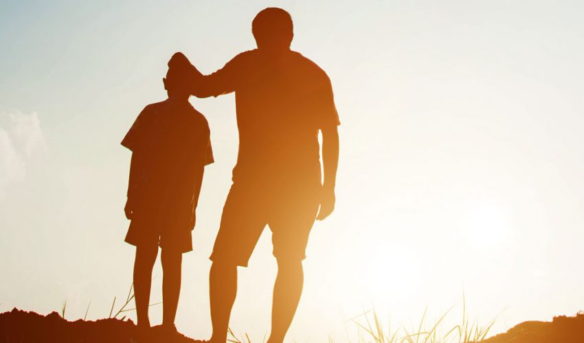 Father and child silhouette at sunset.