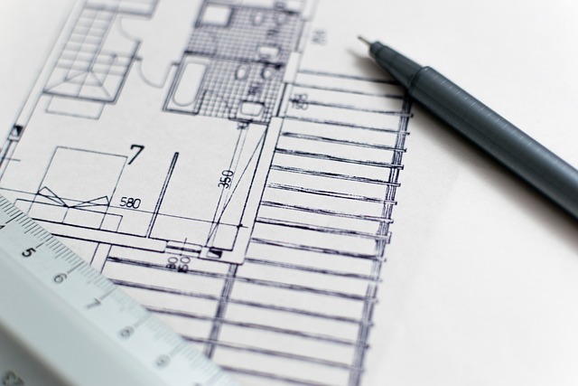 A close-up of architectural blueprints with measurements, a ruler, and a pen.