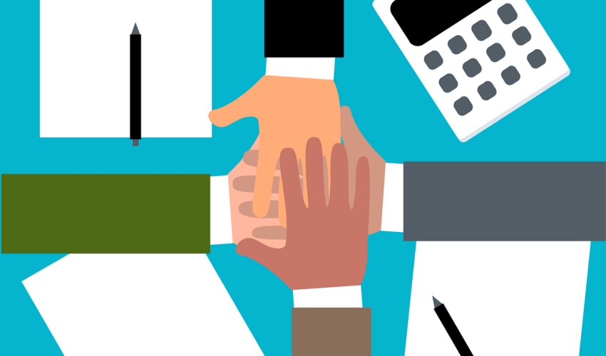 Four hands with different apparent skin tones are stacked in the center, surrounded by papers with pencils and a calculator on a blue background, suggesting teamwork or collaboration.