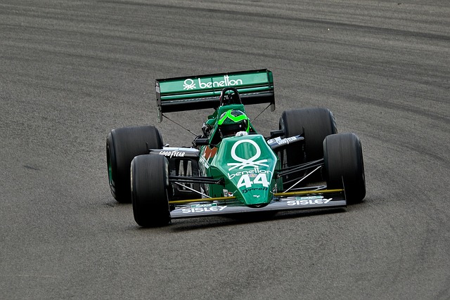 A green Benetton Formula One car with the number 44 on a gray racetrack.